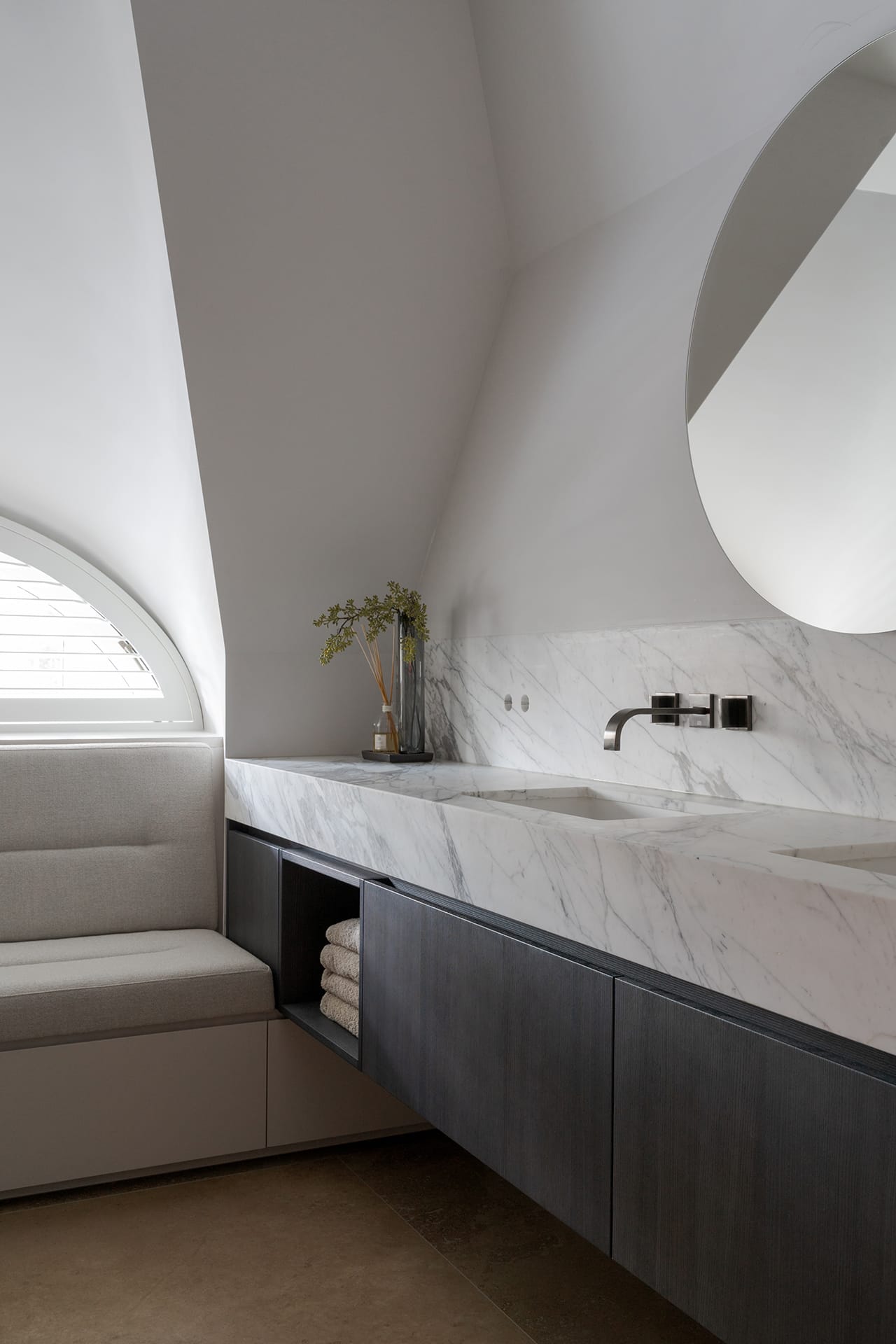 Kinderbadkamer onder een schuin dak met wastafelblad in marmer Calacatta Vagli en een wandkraan van Dornbracht in Dark Platinum matt.