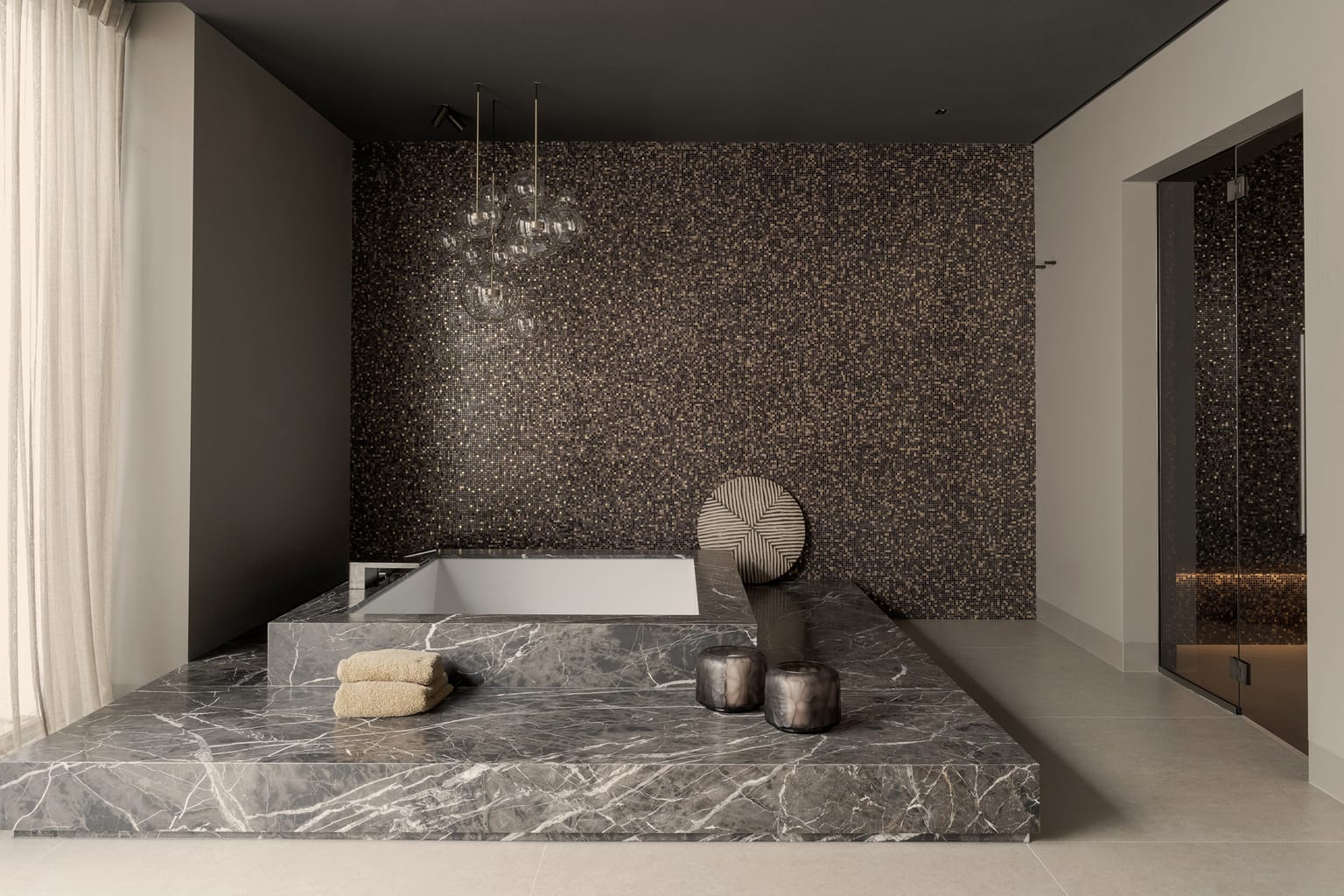 Wellness in de kelder met een bad ingebouwd in marmer Havana Brown, voor een wand van Bisazza-mozaïek met 24-karaats goud.