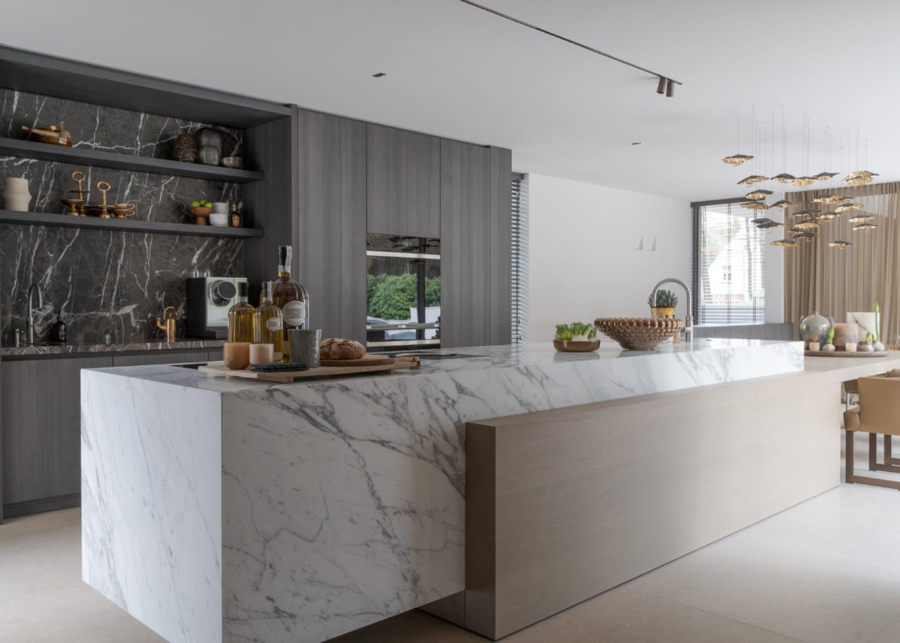 Leefkeuken van Eggersmann met zwevend eiland in marmer Calacatta Vagli en een eikenhouten eettafel die erin doorloopt.