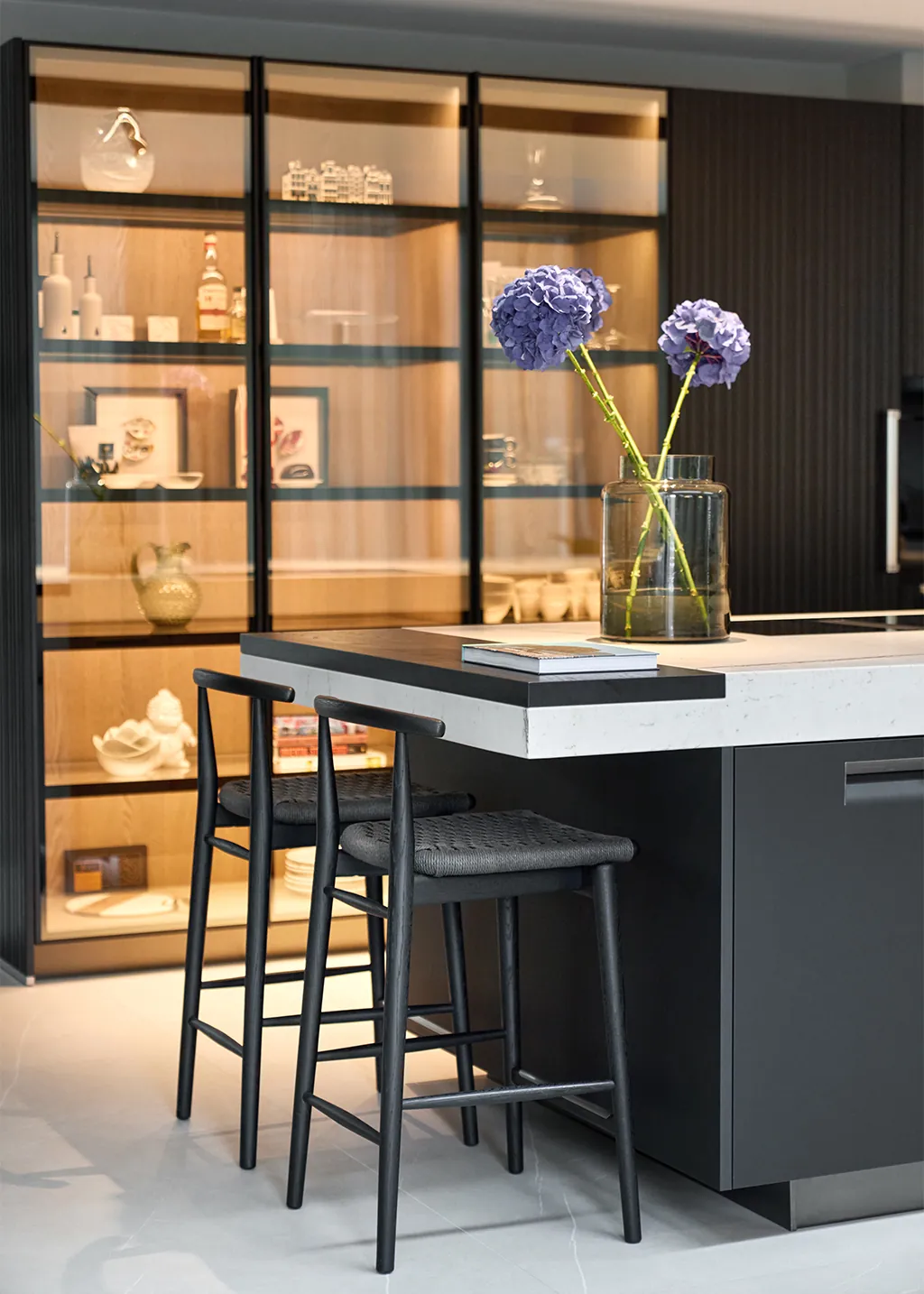 Arclinea Convivium keuken met glazen vitrinekast Bianco Carrara eiland mat zwarte lak fronten en barkrukken