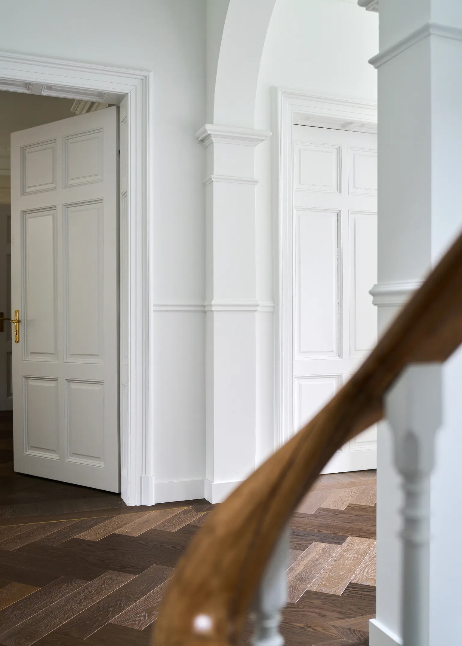 Lichte hal met visgraat houten vloer en witte wandlijsten klassieke elegantie natuurlijke houtstructuur tijdloze uitstraling