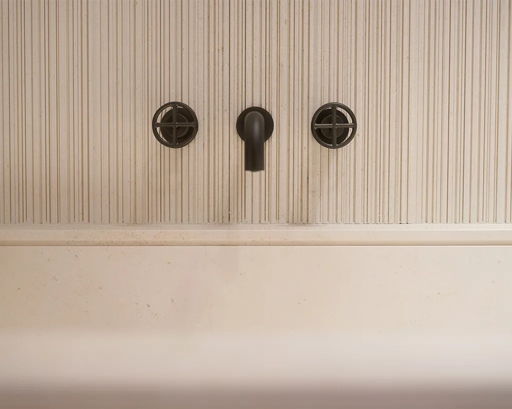 Salvatori Ishiburo bad uit massief Crema d'Orcia natuursteen met CNC freeswerk en Fantini kraan in luxe badkamer